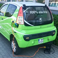 Zielony elektryczny samochód ROMET HE z napisem "100% electric" jest ładowany. To część programu "Mój Elektryk".