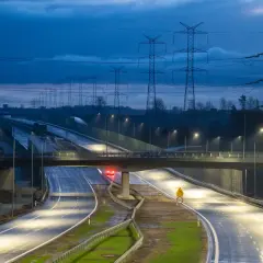 Nowa obwodnica Żukowa nocą, oświetlona latarniami, z linią wysokiego napięcia w tle.