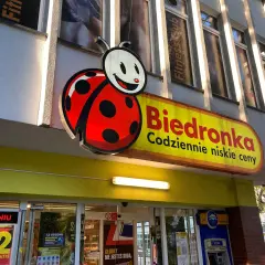 Logo Biedronki i szyld sklepu. Zastanawiasz się, jak odebrać wygraną ze zdrapki Biedronka? Sprawdź w sklepie!