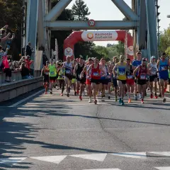 Coureurs au départ du semi-marathon Paris 2026, sous une arche Harmonie Mutuelle. Le soleil brille, les spectateurs encouragent.