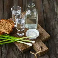 Wódka 0 procent, chleb, szczypiorek i sól na drewnianej desce.