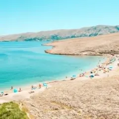 Turkusowe jakie morze jest w Chorwacji? Piękna plaża z ludźmi, parasolami i górami w tle.