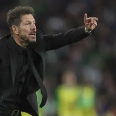 Cholo, trener Atletico Madryt, w czarnym garniturze gestykuluje na boisku, wskazując coś swoim zawodnikom.