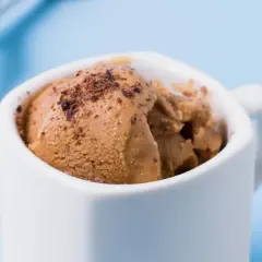 Brązowe lody dla psa w białej filiżance, posypane wiórkami. Gdzie kupić takie smakołyki?