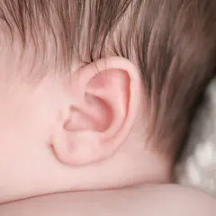 Primo piano dell'orecchio di un neonato, un dettaglio delicato che può essere interessato da otite nei bambini.