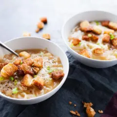 Deux bols de soupe à l'oignon gratinée avec croûtons et ciboule.