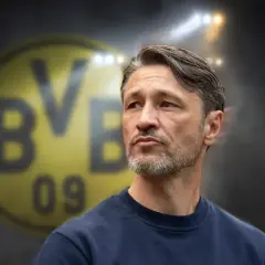 Twarz trenera Borussii Dortmund, z charakterystycznym logo klubu w tle.