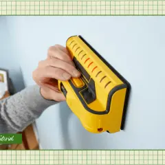 Learn how to use a stud finder to locate wall studs for secure mounting. This yellow tool is pressed against the wall.