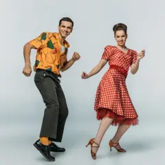 Coppia in abiti vintage che esegue boogie woogie passi e figure con gioia.