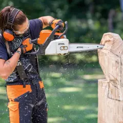 Artiste créant une sculpture bois tronçonneuse facile, des copeaux volent.