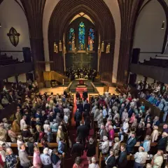 Menschen versammeln sich in einer Kirche für einen evangelischen Gottesdienst. Die evang. Gottesdienstordnung wird vorbereitet.