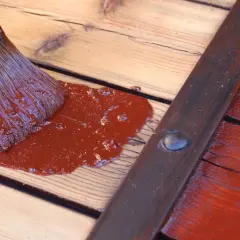 Pinceau appliquant une peinture marron sur des volets en bois sans décaper.