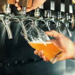 Main d'un barman servant une bière blonde pétillante. Pour comment augmenter la dureté de l'eau, on pourrait ajouter des minéraux.