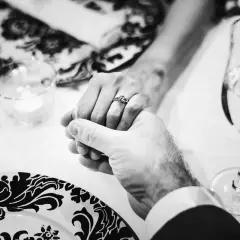 Mani intrecciate, un anello che simboleggia 40 anni di matrimonio smeraldo o rubino. Brindisi con champagne per celebrare un amore duraturo.