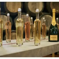 Bouteilles de vin clair et rosé, prêtes pour la création du champagne, avec une bouteille Krug en avant-plan.