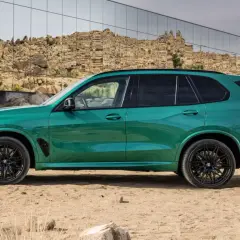 Zielony SUV, idealne ekonomiczne auto na długie trasy, zaparkowany na pustynnym tle z nowoczesnym budynkiem w tle.