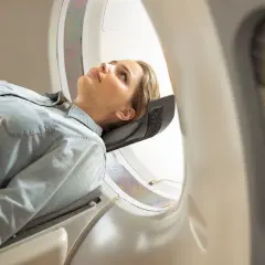 Kobieta leży w aparacie do tomografii głowy, oczekując na badanie.