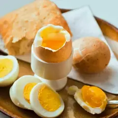Jajka na miękko i pieczywo na talerzu. Czy jajka są lekkostrawne? Tak, zwłaszcza te na miękko, idealne na śniadanie.