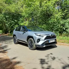 Srebrny Toyota RAV4 Hybrid na leśnej drodze. Zastanawiasz się nad jego spalaniem? Ten SUV oferuje świetne osiągi i niskie zużycie paliwa.