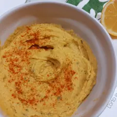 Hummus di ceci senza tahina, cremoso e spolverato di paprika, pronto per essere gustato con una fetta di limone.