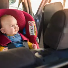 Dziecko w foteliku samochodowym. Po kolizji wymiana fotelika jest kluczowa, zgodnie z przepisami.