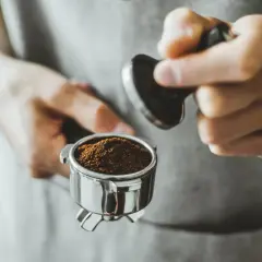 Barista tamped den frisch gemahlenen Kaffee für einen perfekten Kaffee shot.