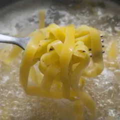 Tagliatelle na widelcu unoszone z wrzącej wody. Prosty sposób, jak ugotować makaron do perfekcji.