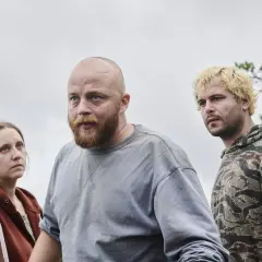 Tre personer, en kvinna och två män, står utomhus i en skogsmiljö. Det är en scen från "Vargasommar del 2".