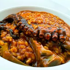 Un delicioso guiso de arroz con pulpo tierno y trozos de alcachofa, todo bañado en una salsa sabrosa.