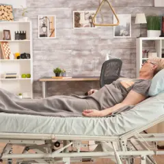 Starsza kobieta leży w łóżku szpitalnym. Dowiedz się, ile wynosi refundacja na materac przeciwodleżynowy, by zapewnić jej komfort.