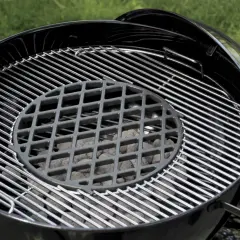 Grill ogrodowy z rusztem i węglem drzewnym.