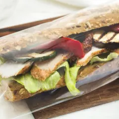 Pan kanapka z kurczakiem, grillowanymi warzywami i sałatą, zapakowana w folię. Idealna na szybki lunch w Warszawie.