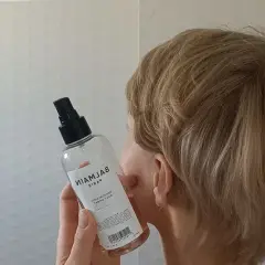 Kobieta z blond włosami trzyma butelkę z atomizerem, która zawiera sól morską do stylizacji włosów.