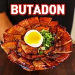 A generous serving of glistening pork donburi, topped with a perfectly soft-boiled egg and chopped green onions.