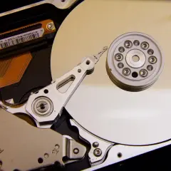 Vue rapprochée de l'intérieur d'un disque dur de PC, montrant le plateau, la tête de lecture/écriture et le moteur. L'emplacement du disque dur PC est essentiel pour le stockage des données.