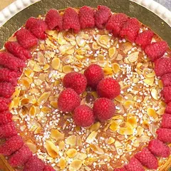 En vacker mandelkaka med citron, toppad med färska hallon och mandelflagor. En härlig sommartårta!