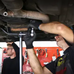 Mechanicy pracują pod samochodem, sprawdzając zawieszenie wielowahacz.