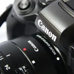 Część czarnego aparatu Canon z obiektywem. Idealna lustrzanka na początek dla każdego pasjonata fotografii.