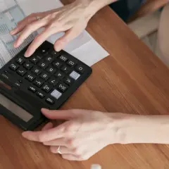 Kobieta liczy rachunek, być może opłatę handlową Energa G11, na kalkulatorze.