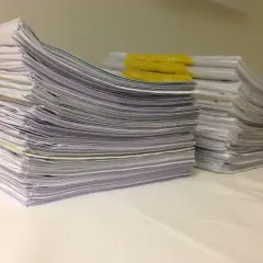 Stosy dokumentów z żółtymi przekładkami na białym tle.
