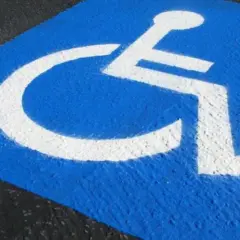 Niebieskie pole z białym symbolem wózka inwalidzkiego. Czy parking dla niepełnosprawnych jest płatny?