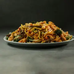 Talerz pełen aromatycznego, smażonego makaronu z krewetkami, wołowiną i brokułami.