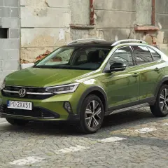 Zielony Volkswagen Taigo na brukowanej ulicy. Sprawdź atrakcyjną vw taigo cena i wybierz swój wymarzony samochód.
