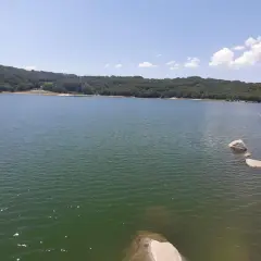 Un lago sereno rodeado de colinas verdes, con rocas en la orilla. Un lugar perfecto para desconectar en Xares a Veiga.