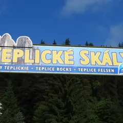 Tablica informacyjna zapraszająca na trasę po skalach w Teplicach. Widoczne skalne formacje i napis "TEPLICKÉ SKÁLY".