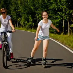 Dziewczyna na rolkach i kobieta na rowerze korzystają ze ścieżki rowerowej.