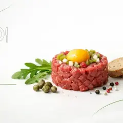 Tatar z surowego mięsa z żółtkiem i dodatkami, obok pieczywo. Czy tatar jest zdrowy? Zależy od składników i sposobu przygotowania.