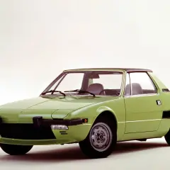 Zielony Fiat X1/9 z czarnym dachem, sportowy samochód z lat 70. na białym tle.