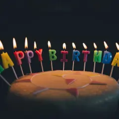 Płonące świeczki w kształcie liter tworzą napis "Happy Birthday". Idealne na życzenia urodzinowe po angielsku.