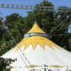 Gelbes und weißes Zirkuszelt mit Sternenmuster, das auf ein Sommerfest im Kulturzelt Kassel hindeutet.